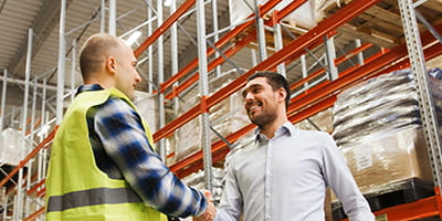 Two people shaking hands in a warehouse